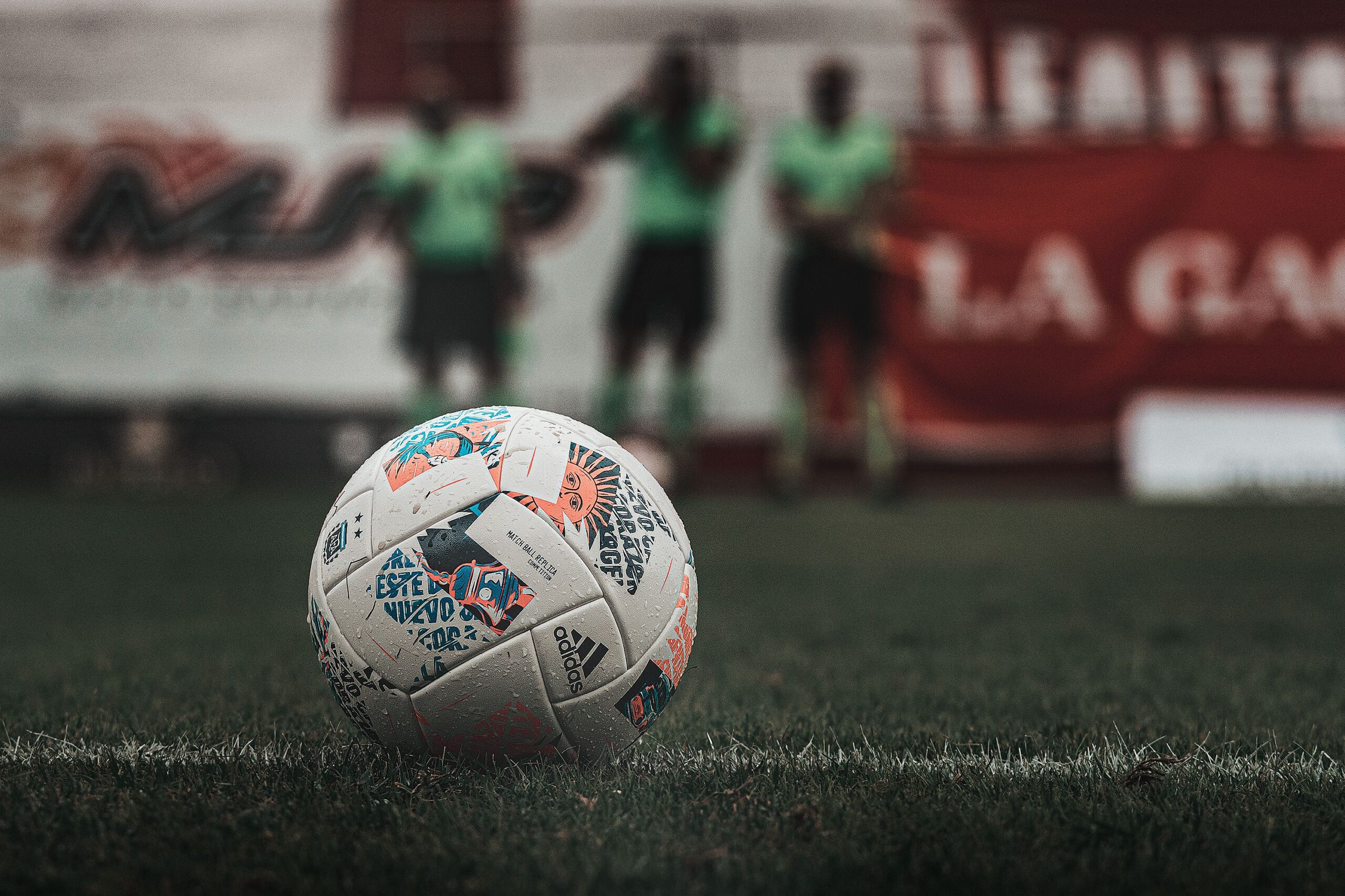 Pelota sobre césped y árbitros desenfocados: fotografía ilustrativa de archivo de 2022, ajena al partido anunciado.