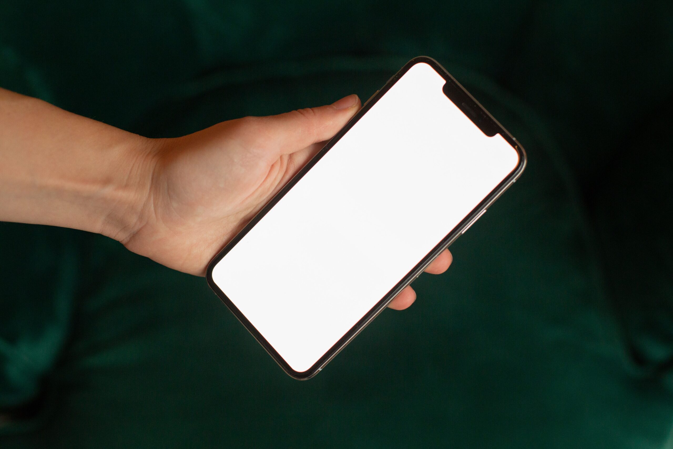 Mano sosteniendo un celular con pantalla blanca; fotografía ilustrativa de archivo, Katrin Bolovtsova/Pexels