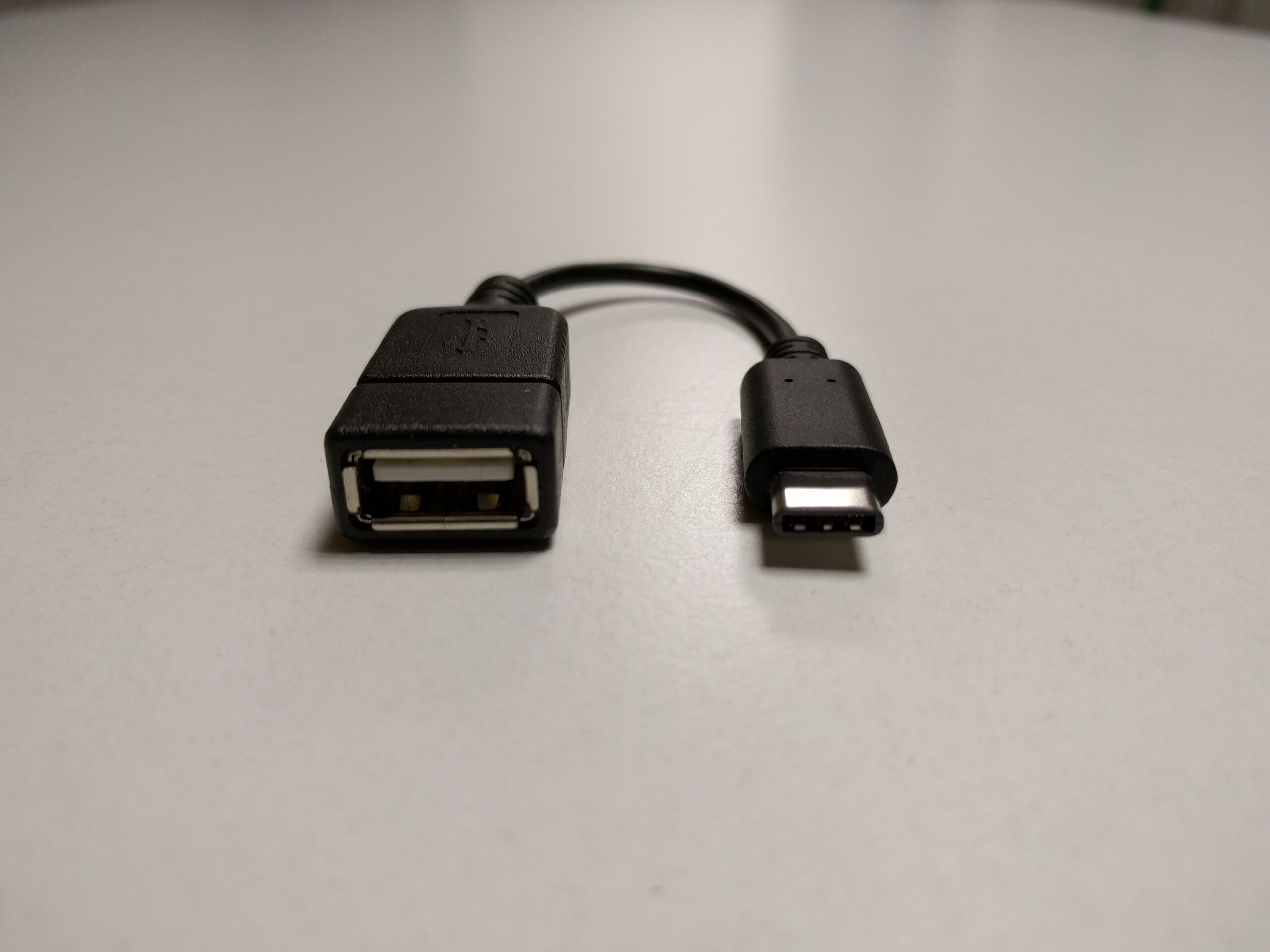 Adaptador USB OTG con conectores USB-A y USB-C sobre una superficie clara. Foto de archivo2016.